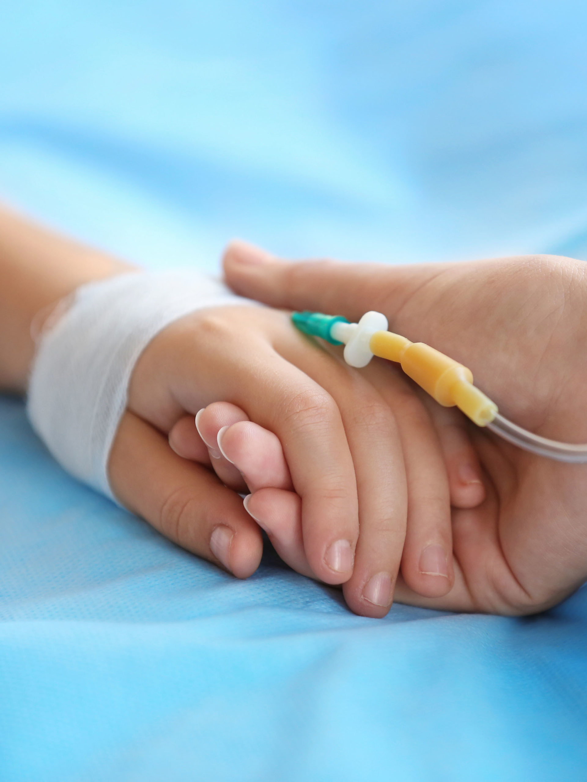 Child hand with IV on bed