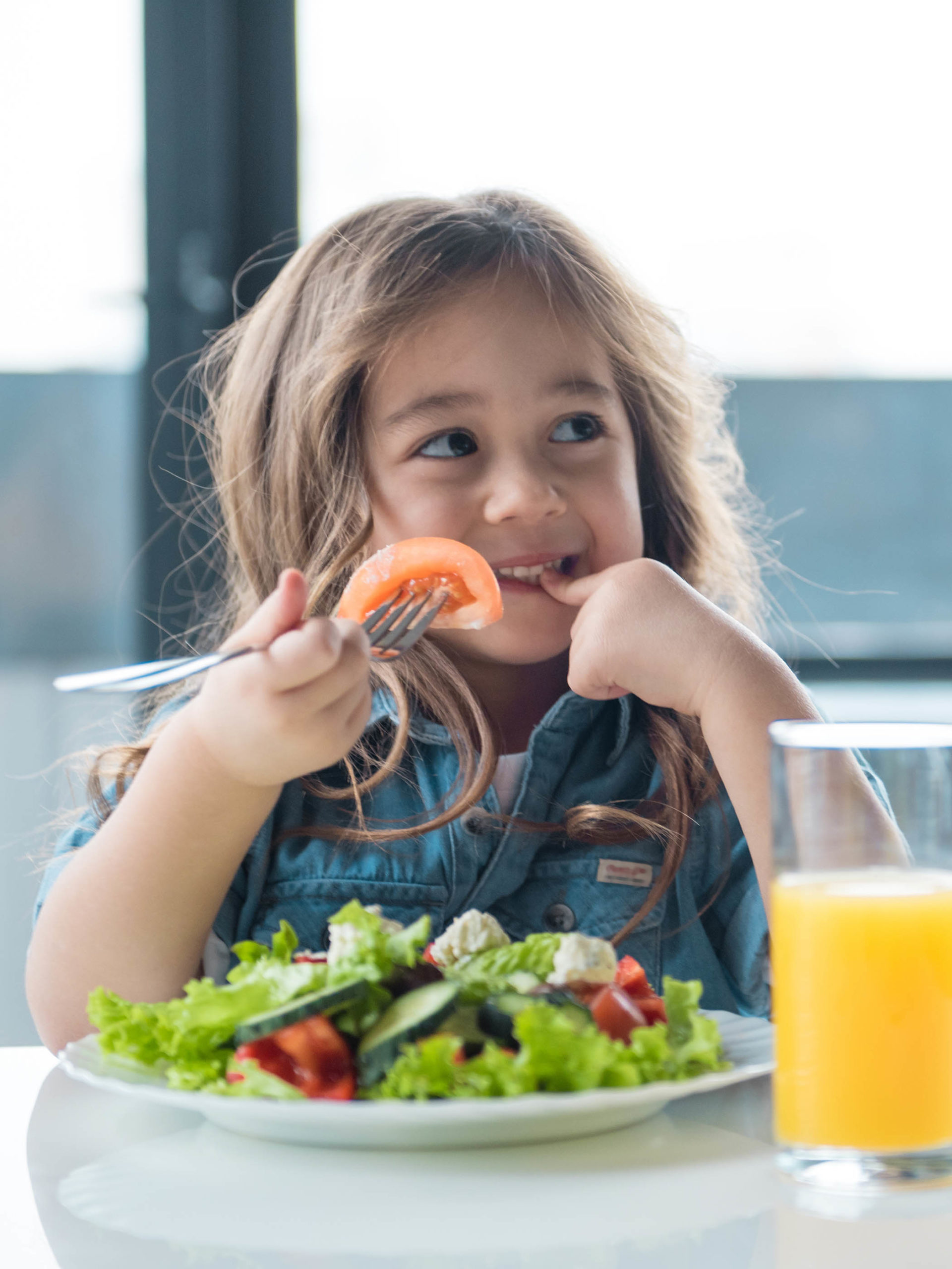 little girl eating a tomato with her salad