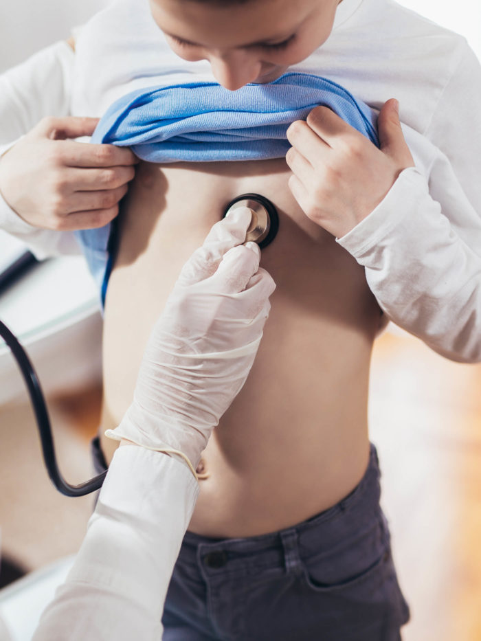 Doctor listening to boy's chest with stethoscope