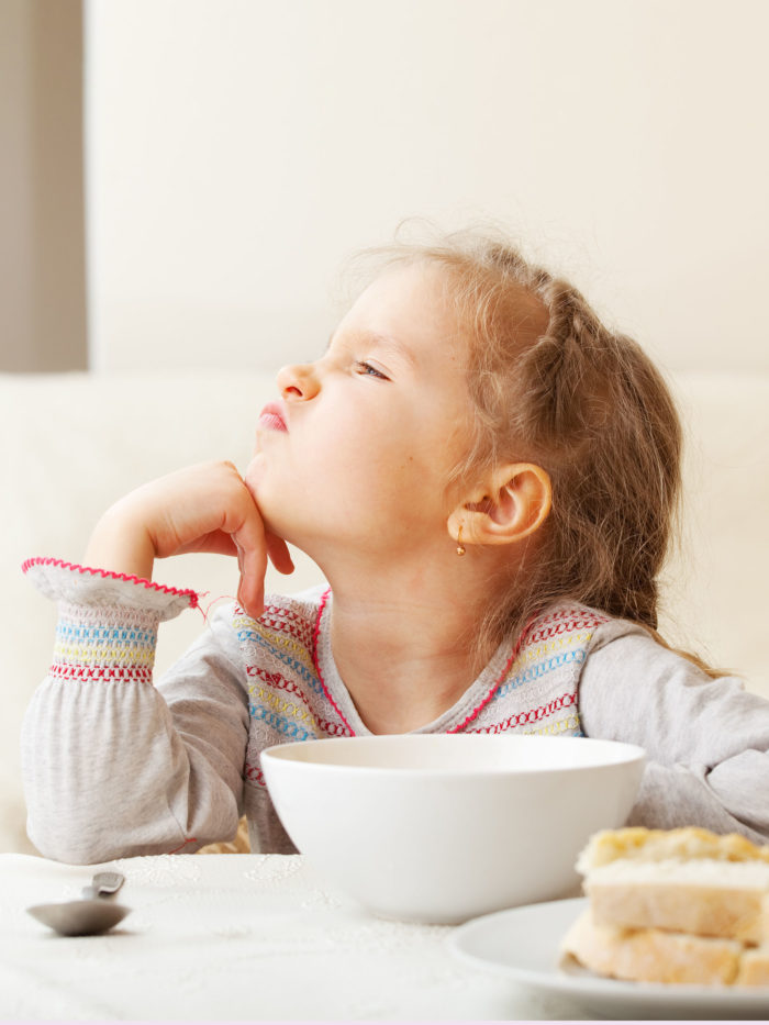 Child looks with disgust at food in bowl