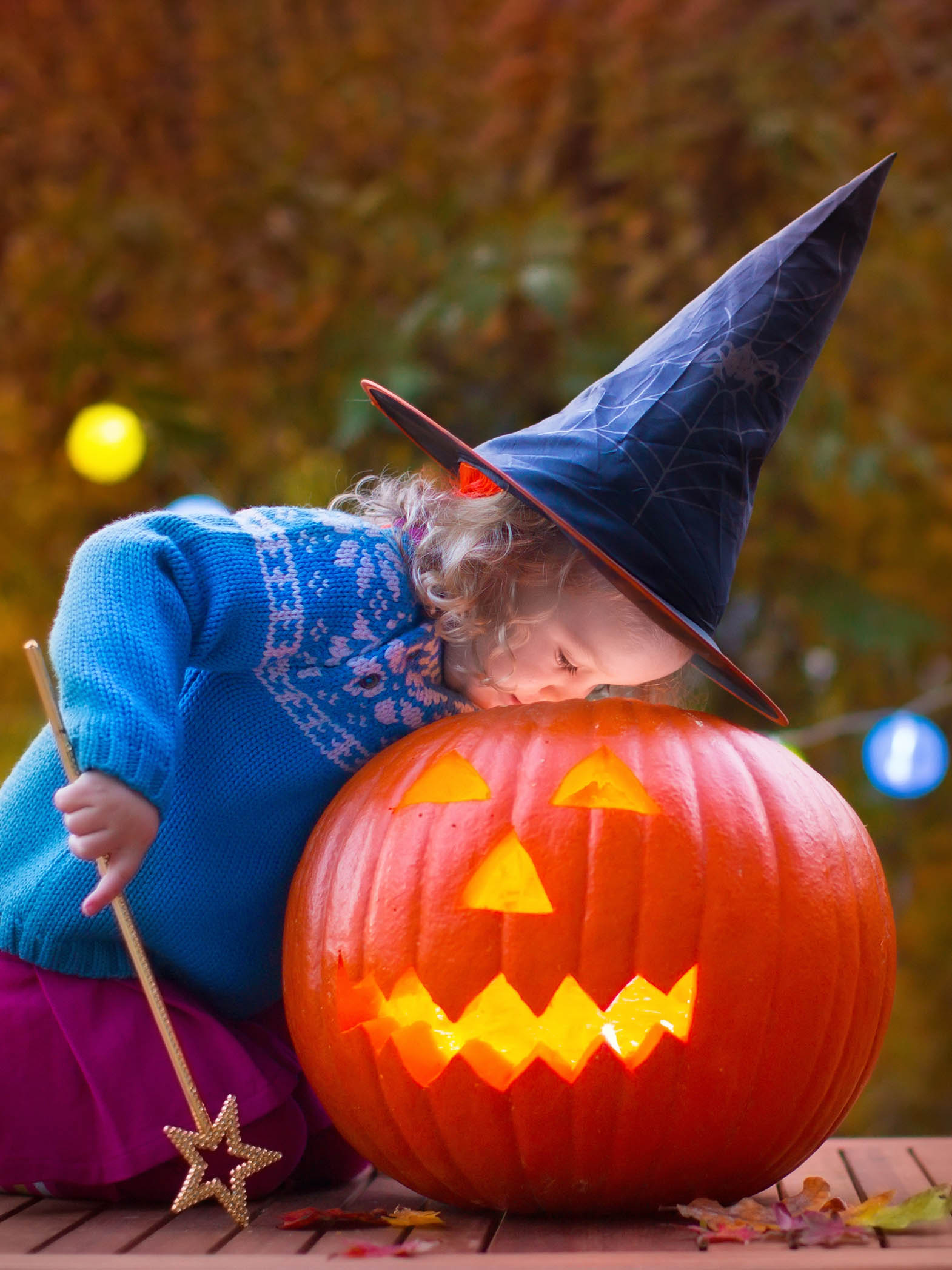 Toddler dressed as witch with jack-o-lantern.