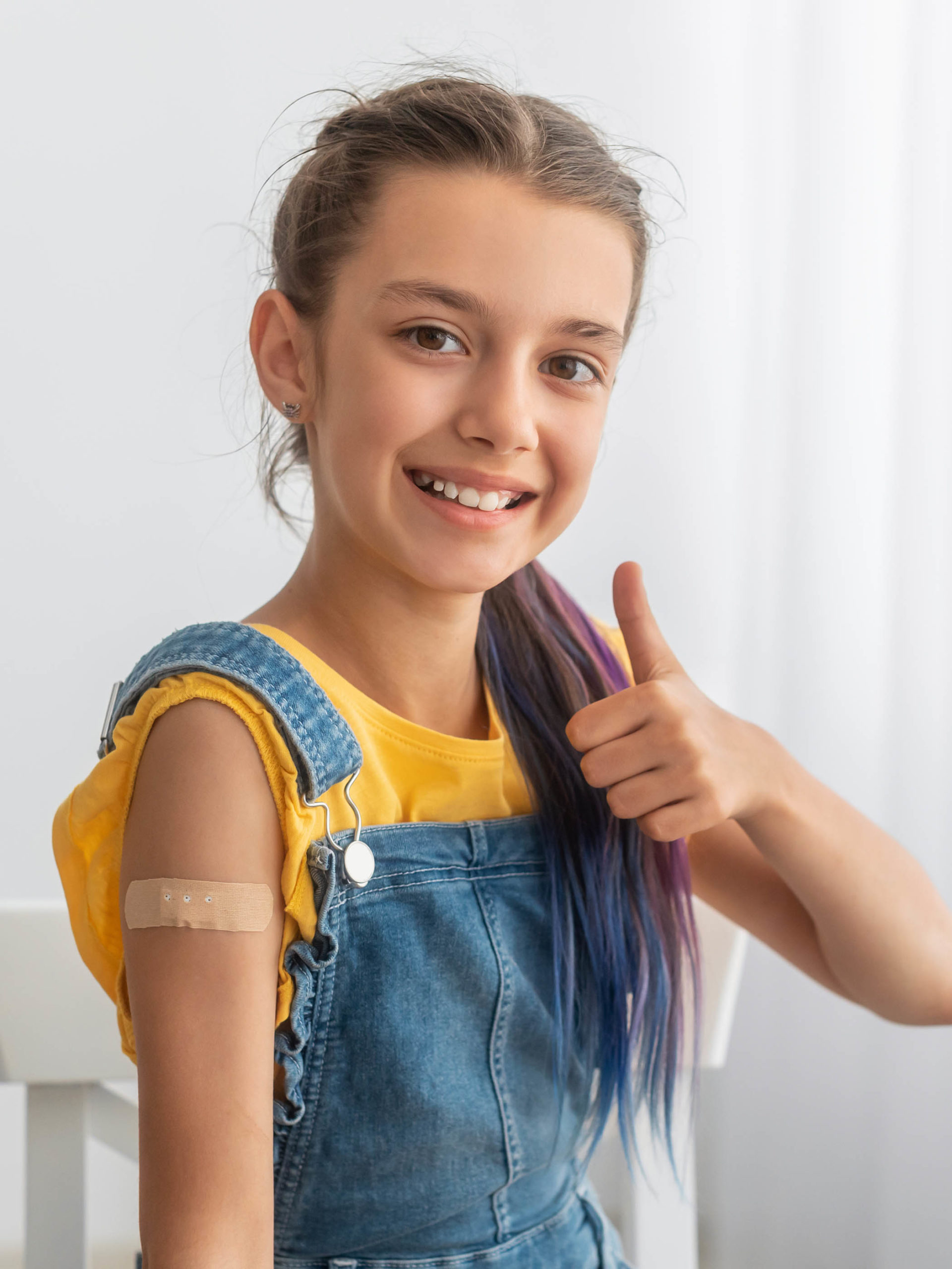 preteen girl wearing a bandage on her arm giving a thumbs up