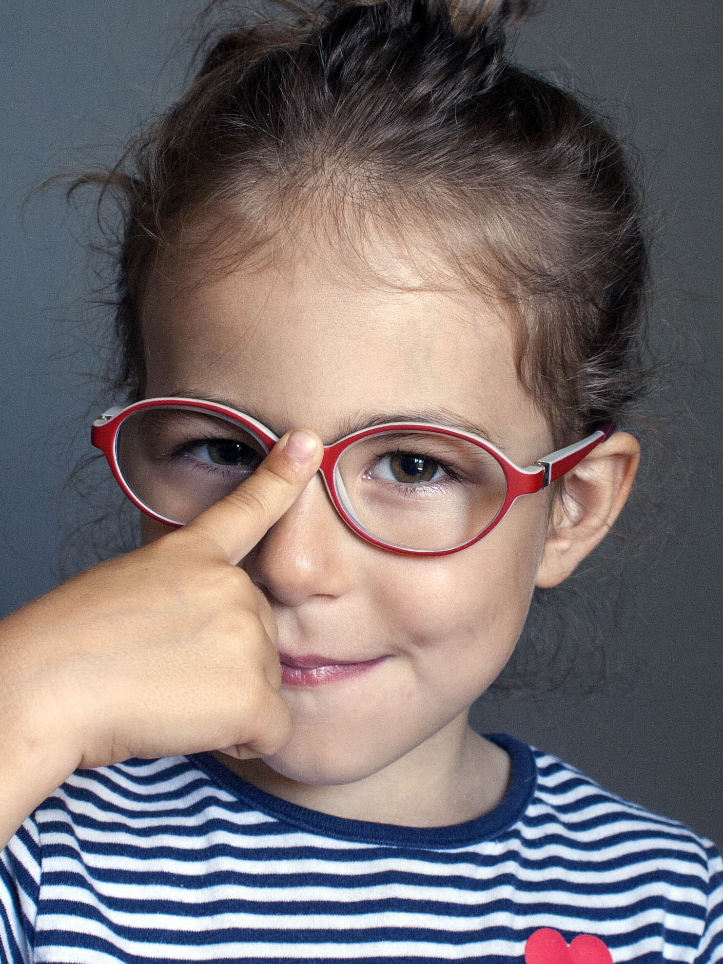 little girl adjusting her glasses with her finger