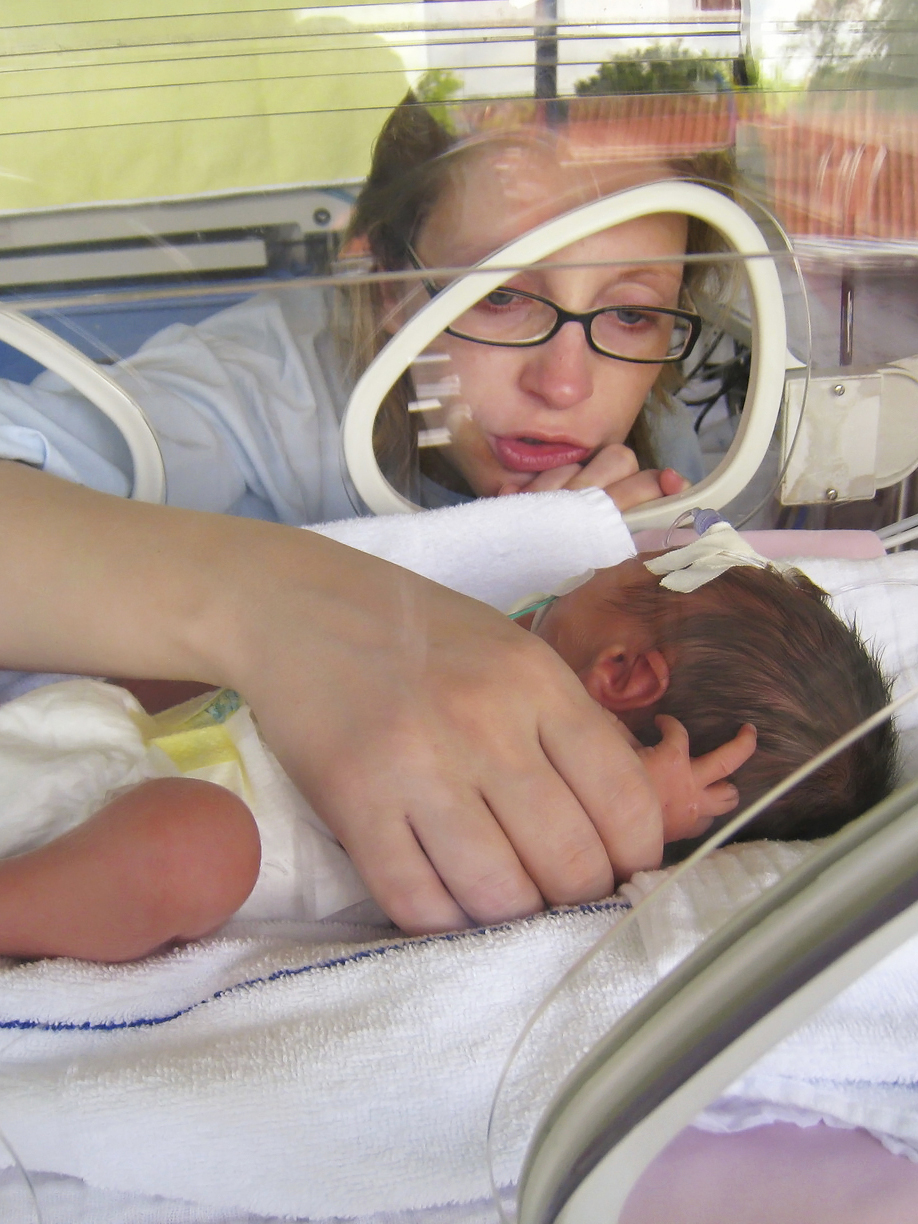 young teen interacting with young new sibling in NICU