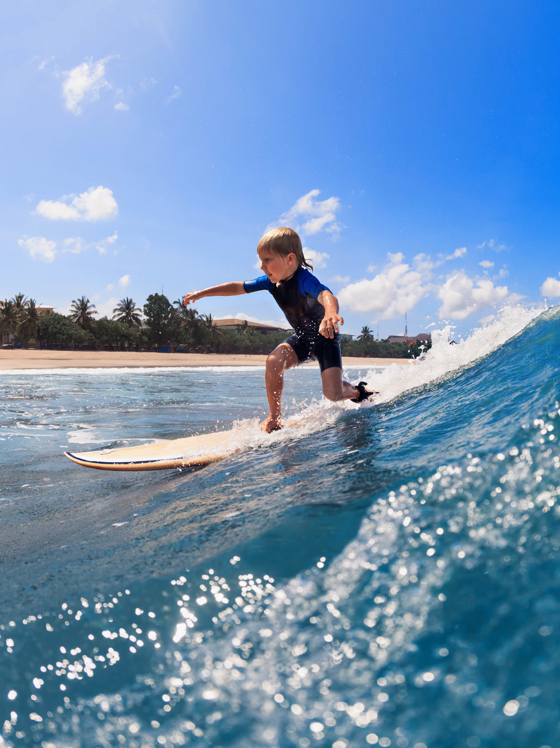 young surfer learns to ride standing up on surfboard