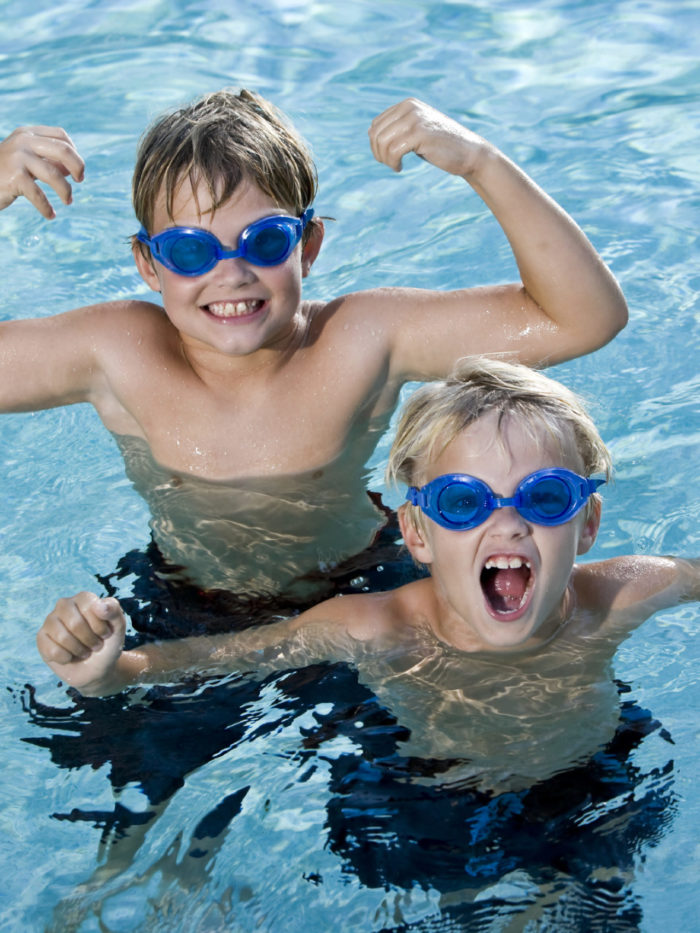 two young boys playing in pool wearing goggles