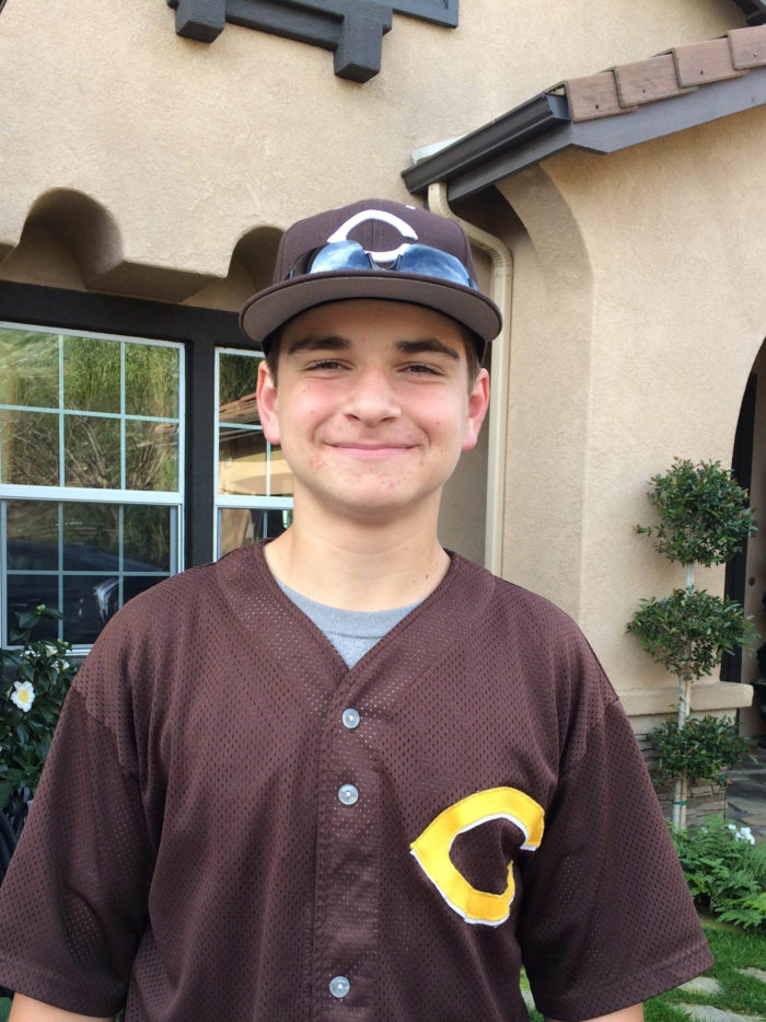 CHOC patient Caron standing outside his house wearing baseball uniform