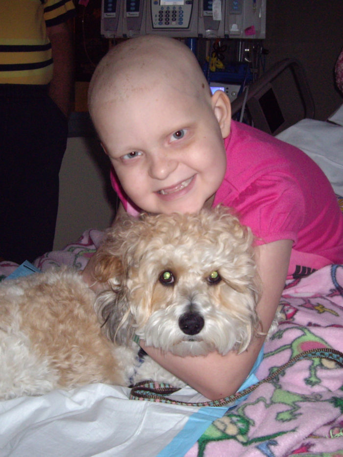 CHOC patient Timmaree cuddling with therapy dog in hospital bed