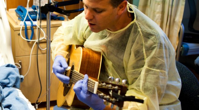 Eric Mammen, Lead music therapist, playing his guitar for a patient