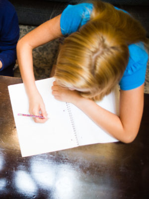 Teen girl doing homework, writing in a notebook