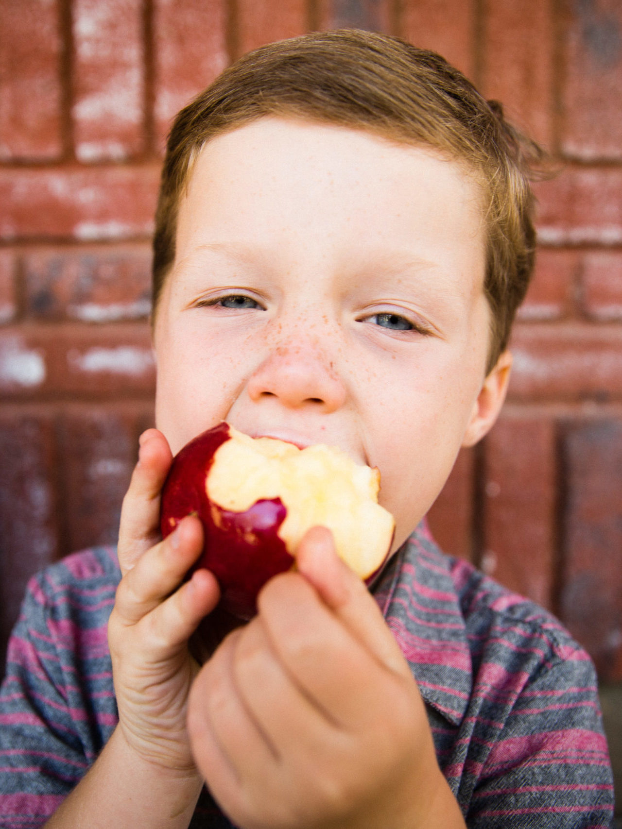 School boy taking a big bite into an apple