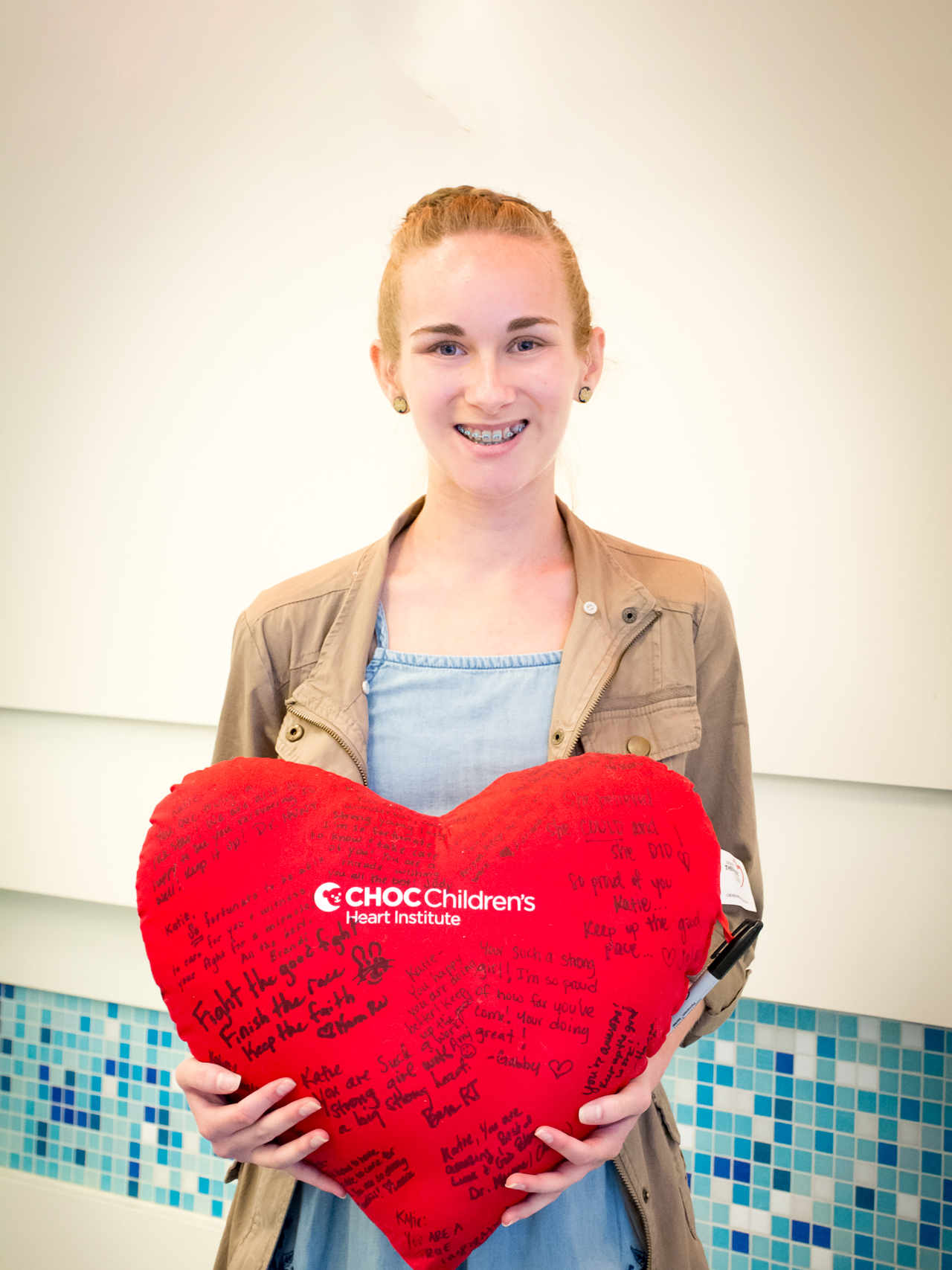 CHOC heart patient holding a heart-shaped pillow autographed with well wishes