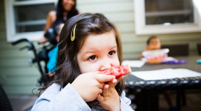 Little girl eating watermelon outdoors