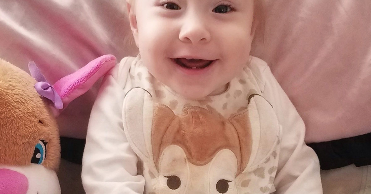 CHOC patient Michelle smiling, sitting on her bed, around her first birthday