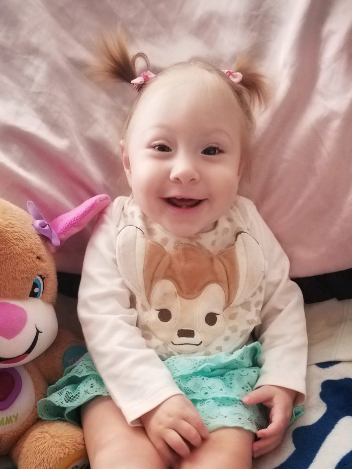 CHOC patient Michelle smiling, sitting on her bed, around her first birthday