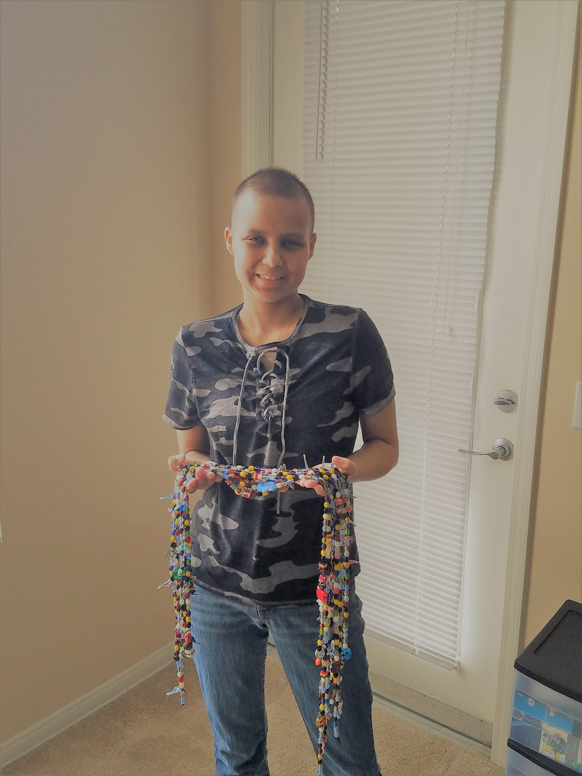 CHOC oncology patient Emma posing with strings of beads in her hands