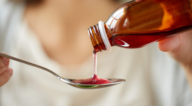 Closeup of parent pouring child's medicine onto a kitchen spoon