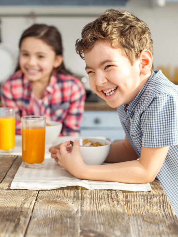 Siblings eating breakfast together in kitchen