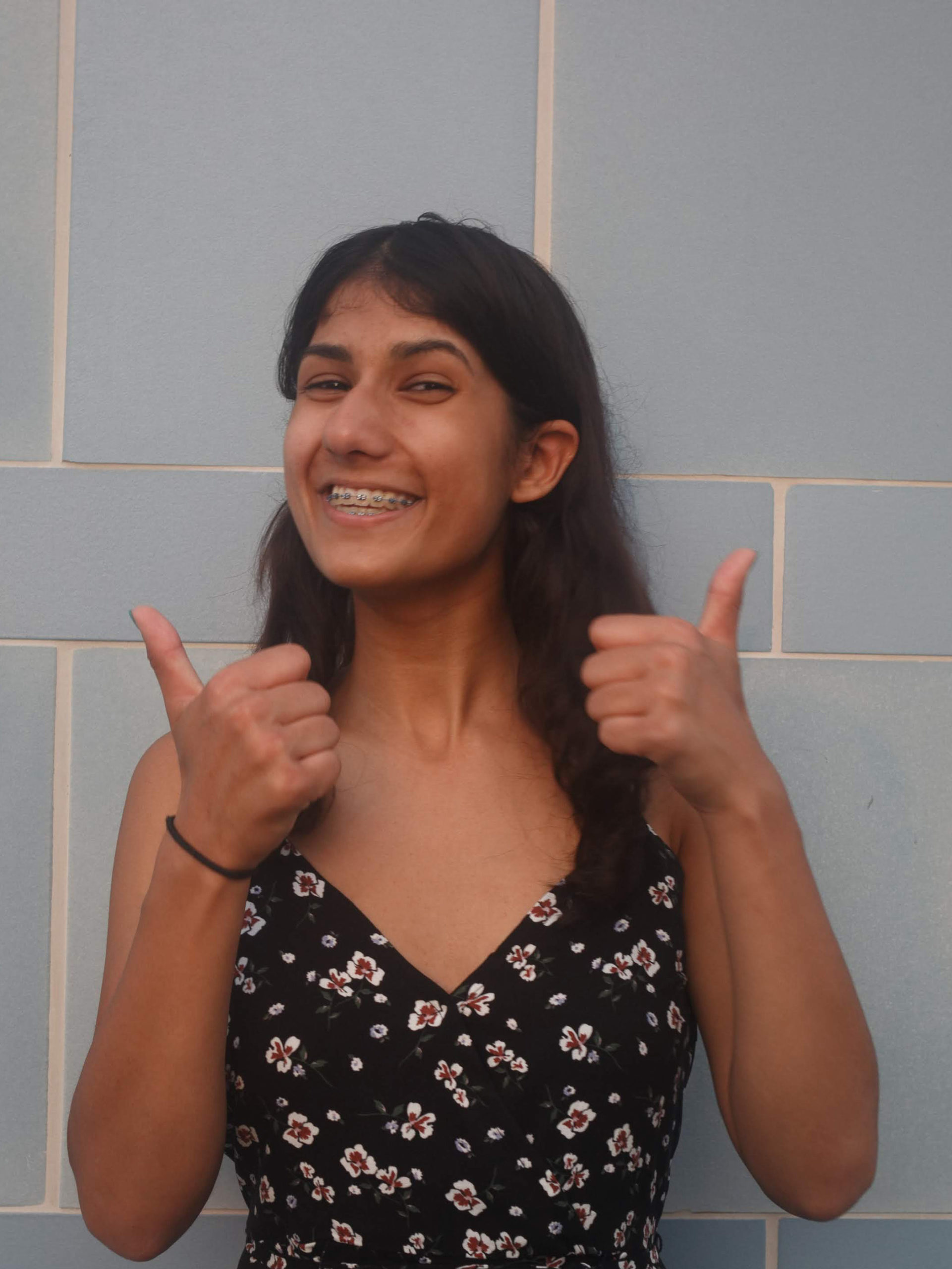 Diyya smiling at the camera with two thumbs up