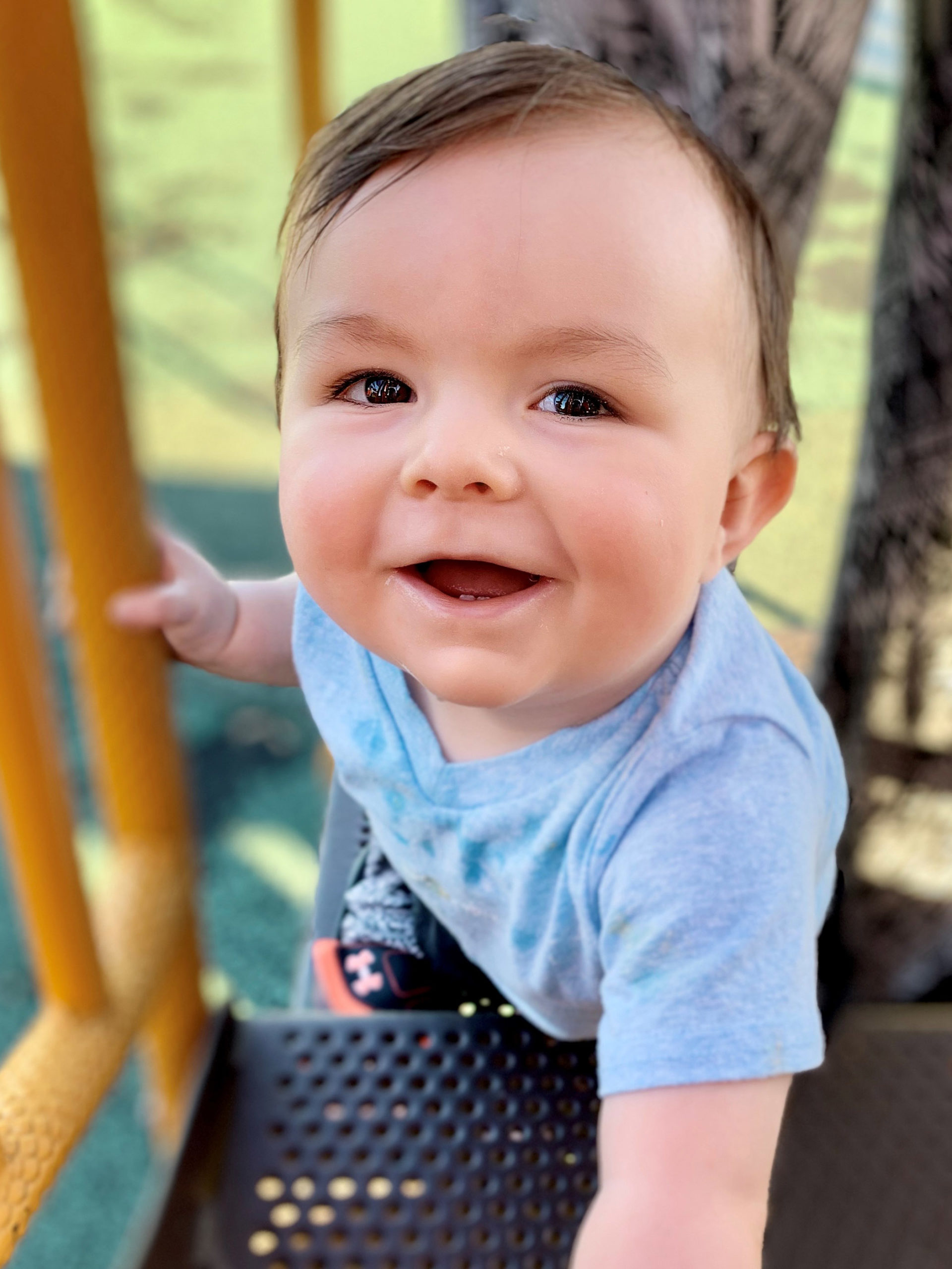 Tavik smiling at the camera while playing on a playground