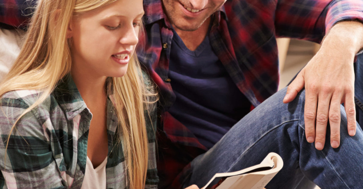 Father and daughter sitting on the floor reading