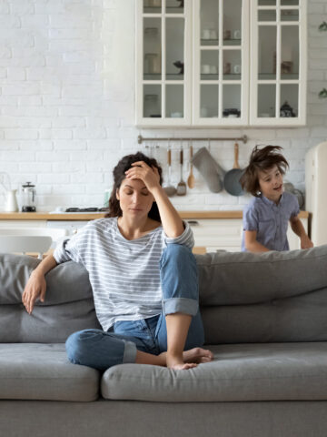 Parent looks stressed while child runs in background - how parents can deal with COVID-19 stress