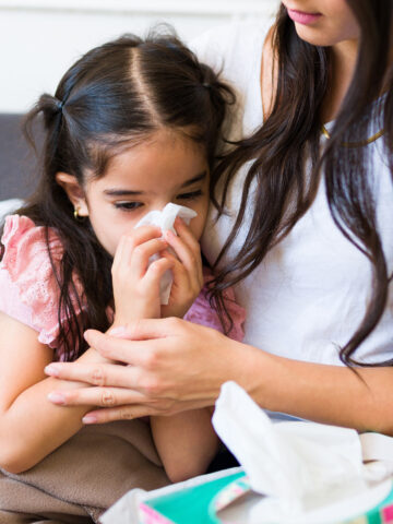 Madre con hija enferma sonándose la nariz