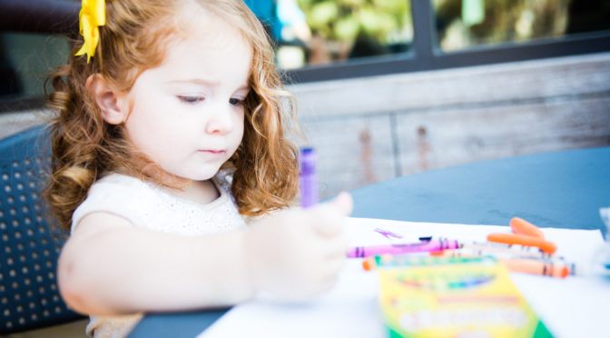 Toddler coloring with crayons outdoors