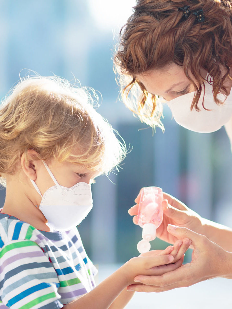 mom and child wearing masks using hand sanitizer