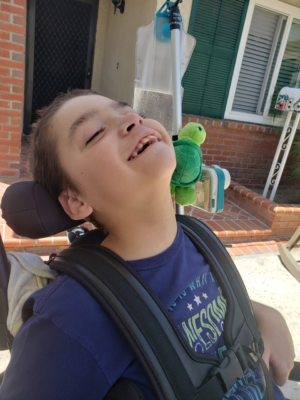 CHOC patient Robert smiling in his wheelchair outside
