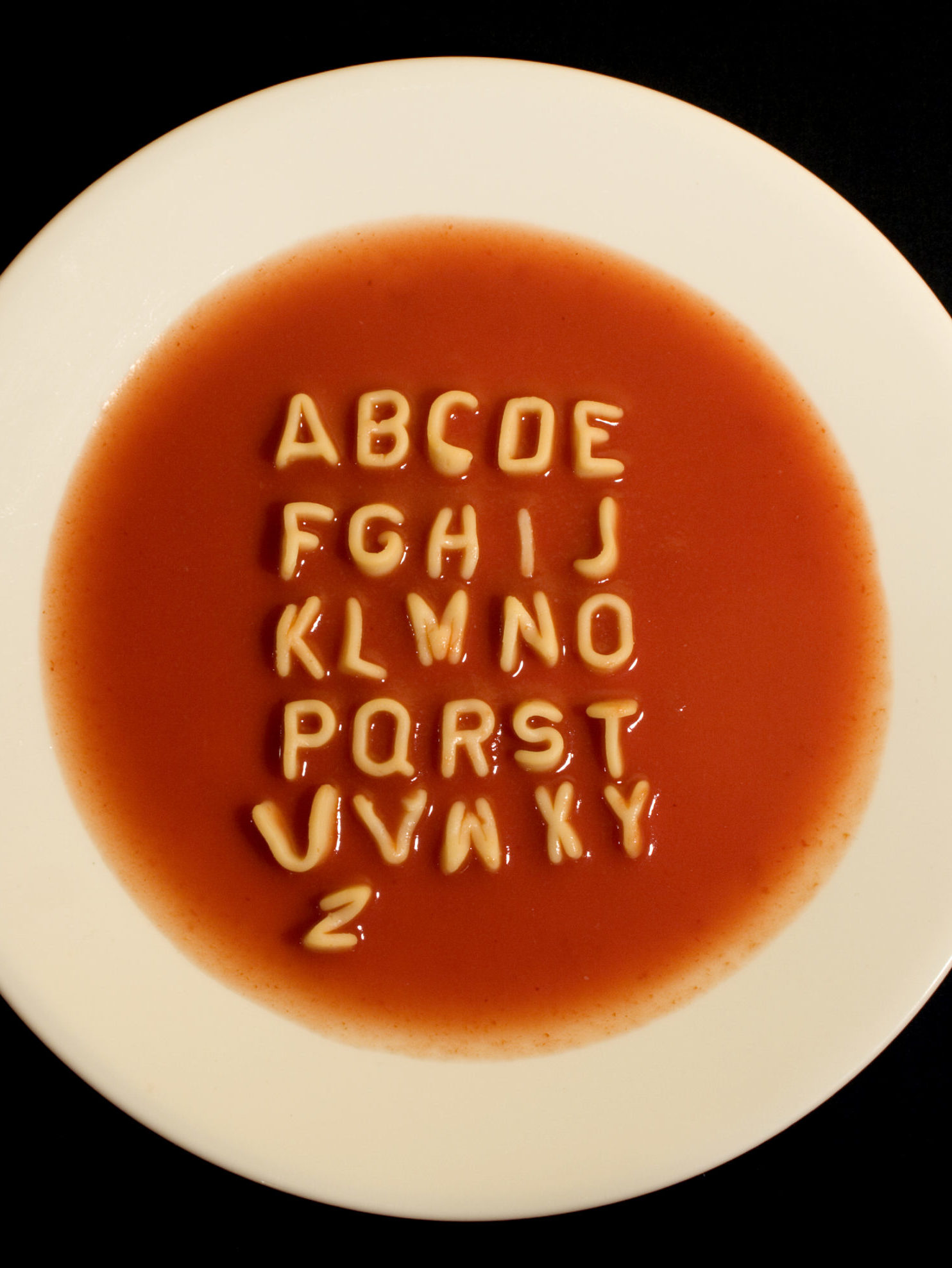 Alphabet soup letters are laid out in a tomato soup to spell the alphabet.