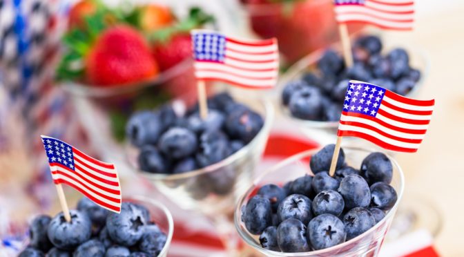 blueberries in a cup with an American flag toothpick