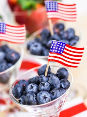 blueberries in a cup with an American flag toothpick