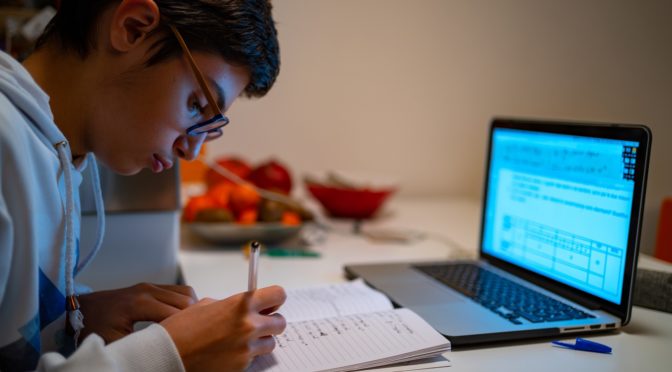 teenage boy doing homework on laptop