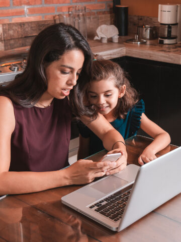 Madre e hijo miran la computadora portátil durante la cita de telesalud