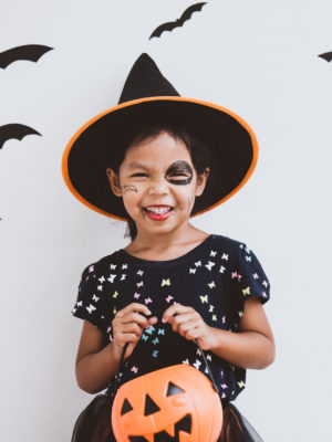 little girl dressed up as a witch for halloween with pumpkin bucket