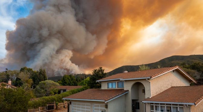 neighborhood by hills with wildfire closing in