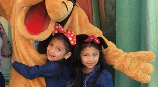 Naomi and twin sister Natalie at Disneyland with Pluto