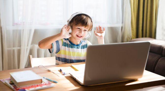child wearing headphones for virtual learning call on laptop