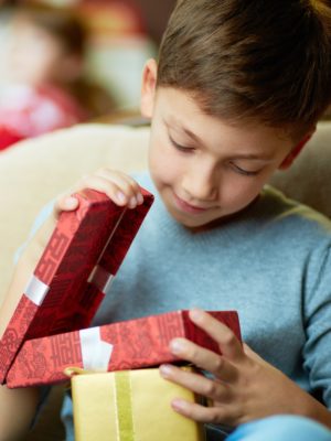 young boy opening wrapped holiday gift