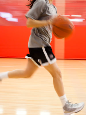 Athlete in black shorts running with basketball