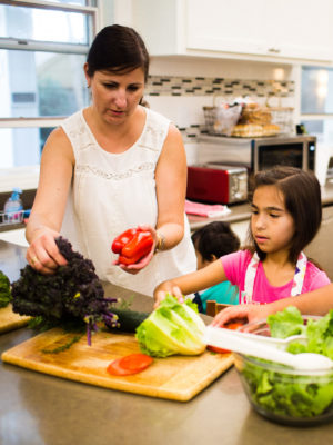 mother and daughter chopping vegetables for a salad together