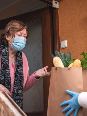 Volunteer during pandemic delivering groceries to senior woman