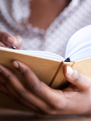 close up portrait of female hands holding pen and journal