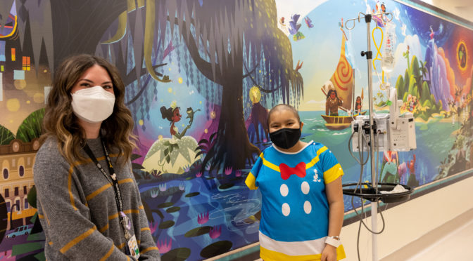 CHOC patient Melanie standing in front of Disney mural at CHOC