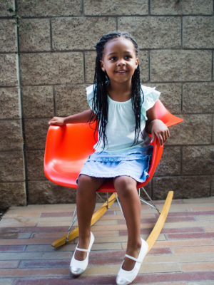 Smiling little girl sitting on rocking chair outdoors