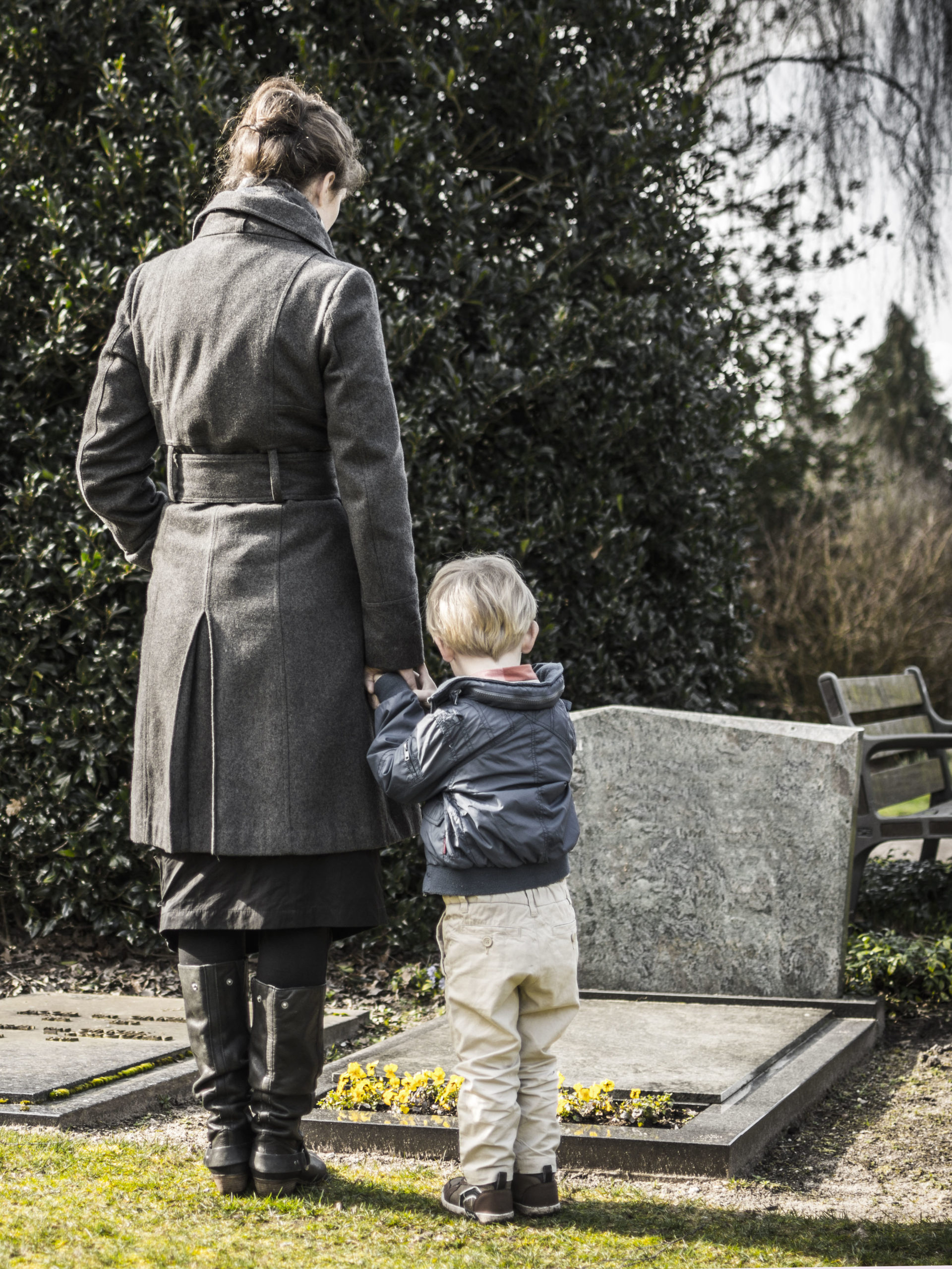 Woman with child at graveyard, staring at tombstone