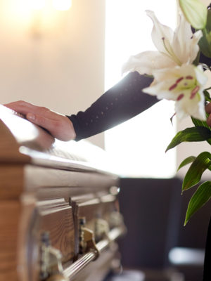 woman with white lily flowers and coffin at funeral in church