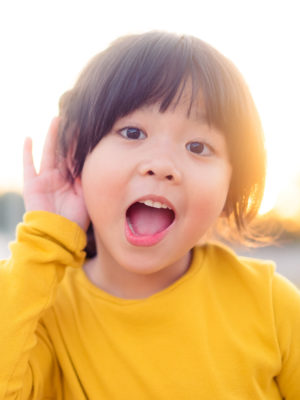 girl holds her hand near her ear to listen better