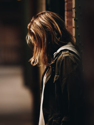 teen in dark clothing with hair covering face